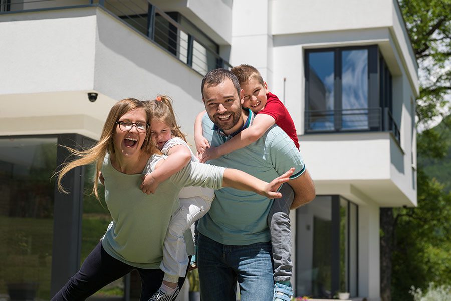 Personal Insurance - Portrait Of Excited Family Standing Outside Modern Home